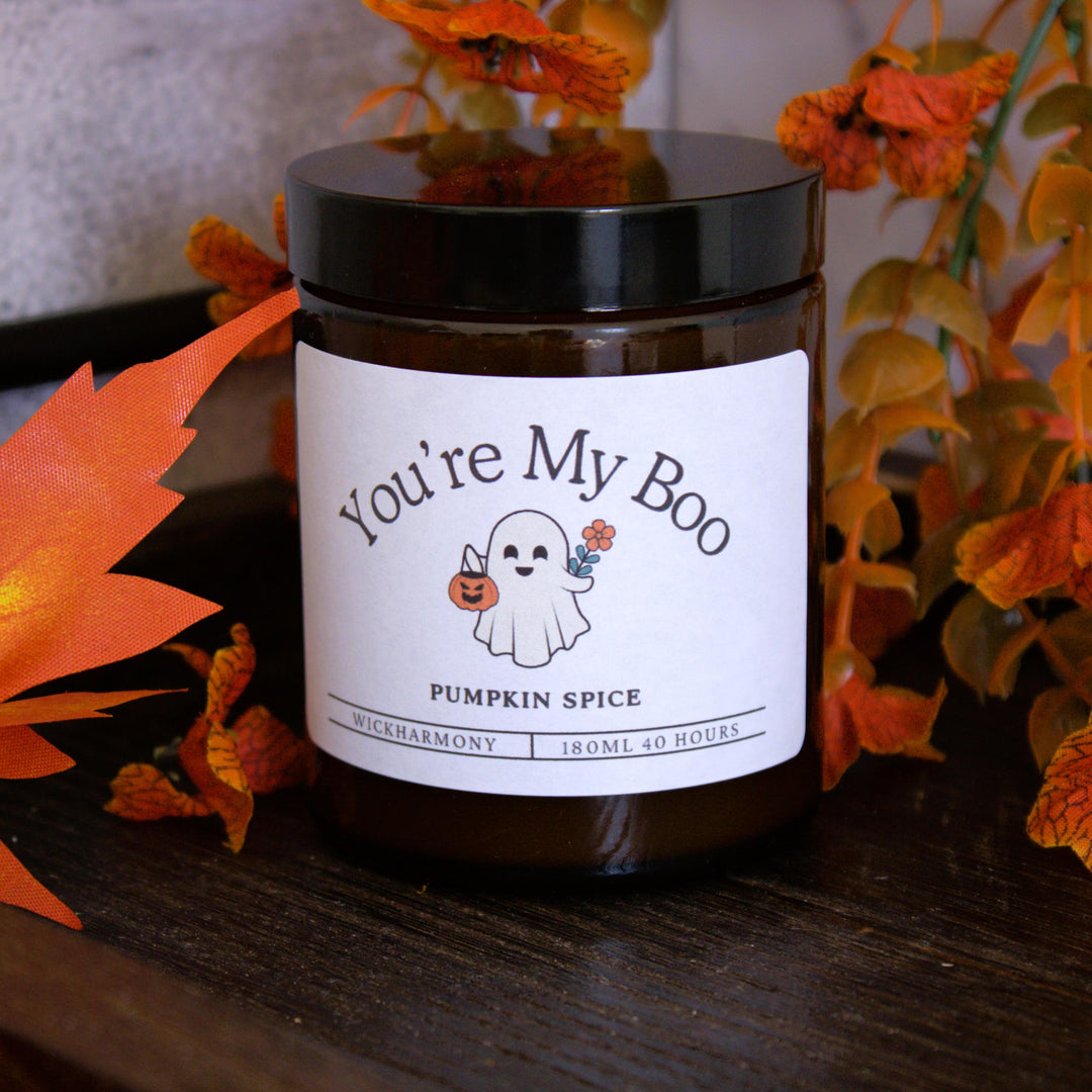 Pumpkin spice candle labeled 'You're My Boo' with Halloween-themed design on a wooden surface.