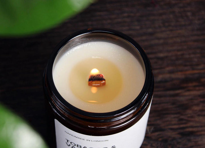 Candle in a jar with a small flame on a dark surface