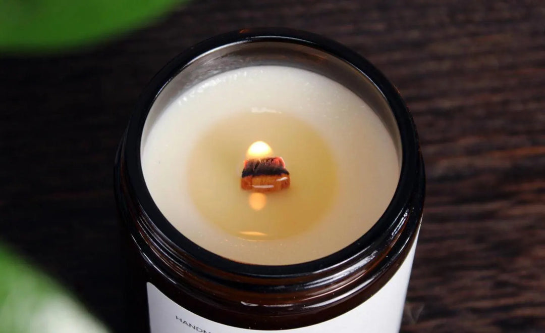 Candle in an open jar with a small flame on a wooden surface